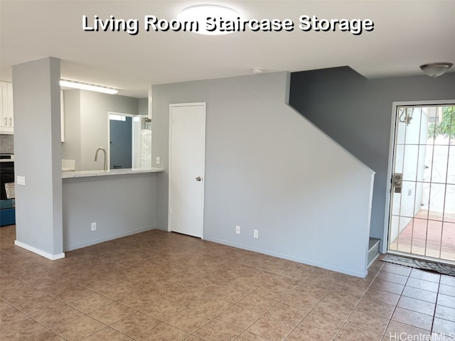 unfurnished living room featuring sink and light tile patterned floors