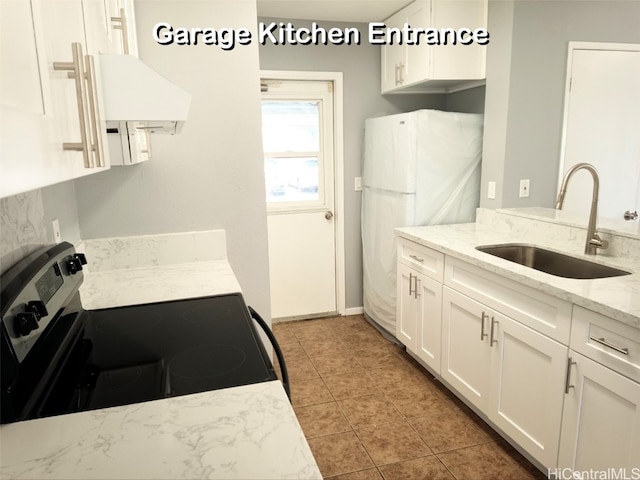 kitchen featuring electric stove, sink, light stone countertops, white cabinets, and white fridge