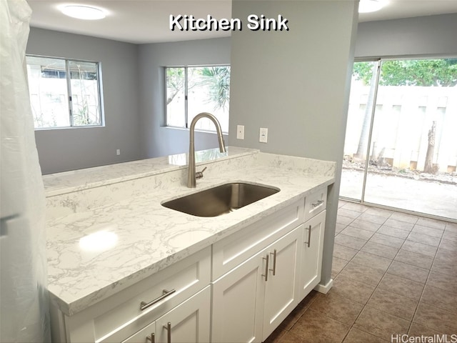 kitchen with white cabinetry, sink, tile patterned flooring, and light stone countertops