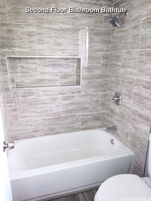 bathroom featuring toilet and tiled shower / bath combo