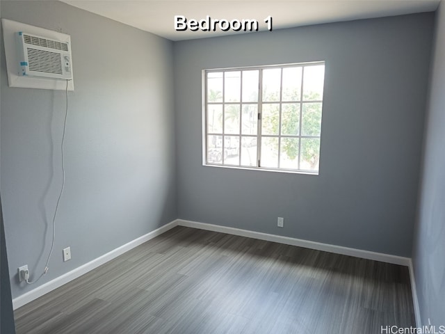 spare room featuring hardwood / wood-style floors and a wall unit AC