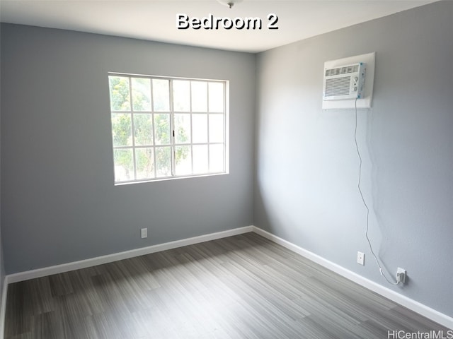 empty room with wood-type flooring and a wall unit AC