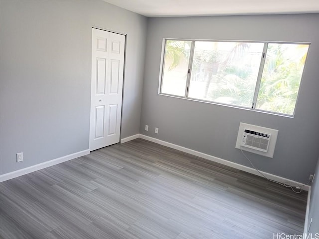 empty room with wood-type flooring and an AC wall unit