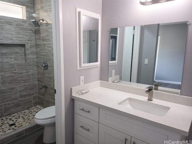 bathroom featuring vanity, toilet, and tiled shower