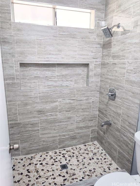 bathroom featuring a tile shower and toilet