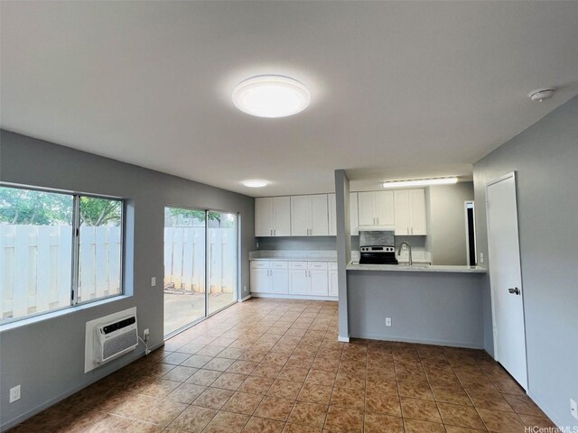 91-1021 Kuina St Unit 119, Ewa Beach, HI 96706 - kitchen featuring light countertops, a wall unit AC, a sink, stainless steel electric stove, and white cabinetry