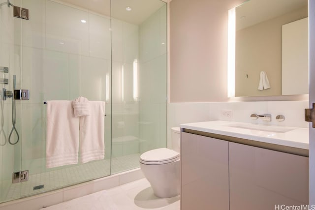 bathroom with toilet, vanity, and a shower with door