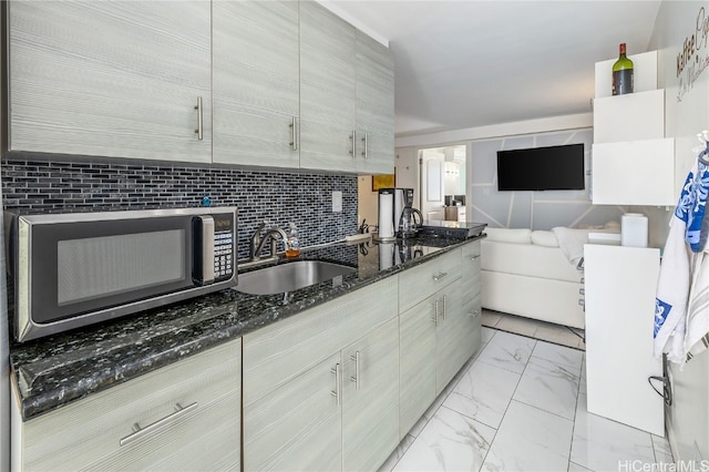 kitchen featuring sink, dark stone counters, and backsplash