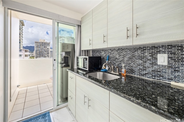 kitchen featuring sink, decorative backsplash, and dark stone counters