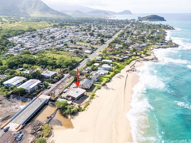 drone / aerial view with a water and mountain view and a view of the beach