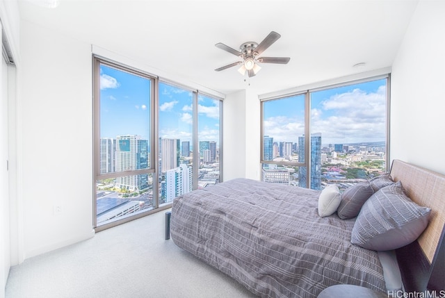 bedroom featuring carpet flooring, ceiling fan, multiple windows, and floor to ceiling windows