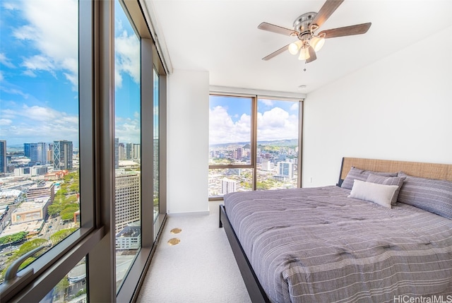 bedroom featuring ceiling fan, light carpet, expansive windows, and access to exterior