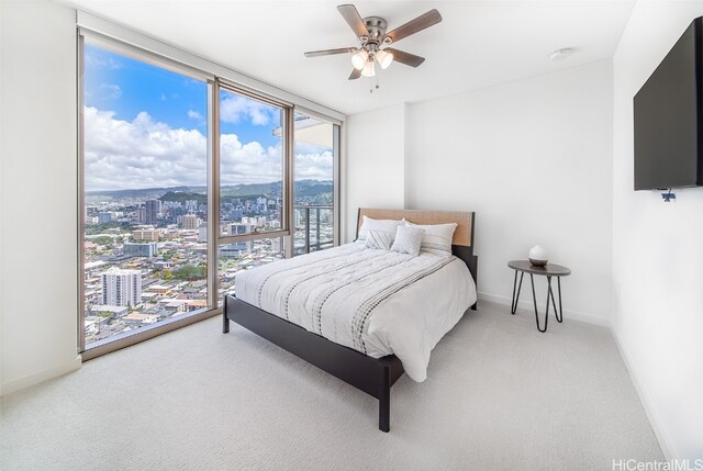 carpeted bedroom featuring a wall of windows and ceiling fan