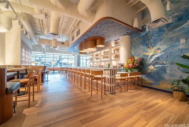 dining space with light hardwood / wood-style flooring and bar area