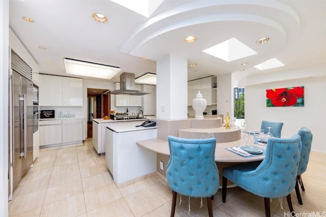 kitchen featuring white cabinetry, island range hood, kitchen peninsula, pendant lighting, and white microwave