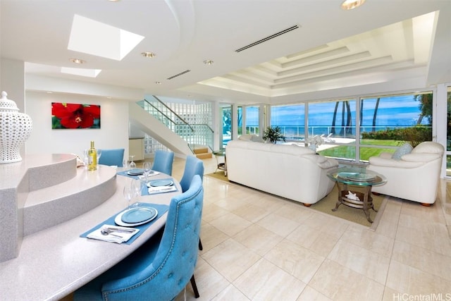 living room with light tile patterned floors, a skylight, and a raised ceiling