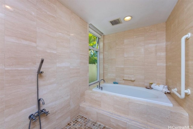 bathroom with shower with separate bathtub and tile walls