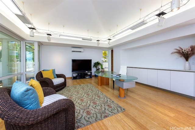 living room featuring a wall mounted air conditioner, a towering ceiling, and light wood-type flooring