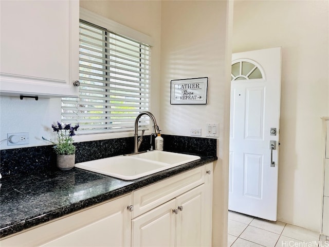 kitchen featuring white cabinetry, sink, dark stone counters, and light tile patterned floors