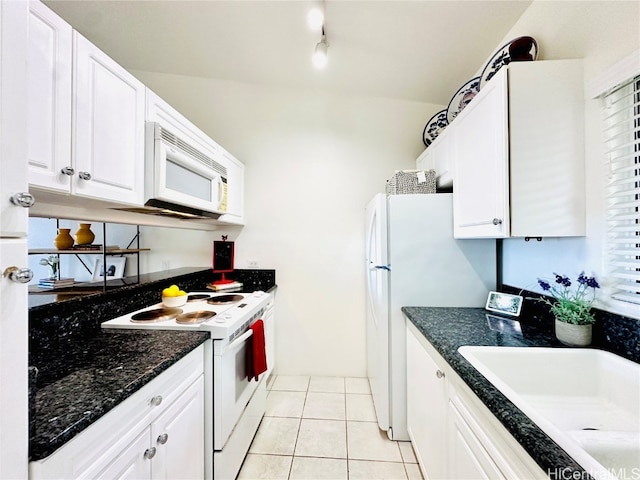 kitchen featuring light tile patterned floors, white cabinetry, dark stone countertops, sink, and white appliances