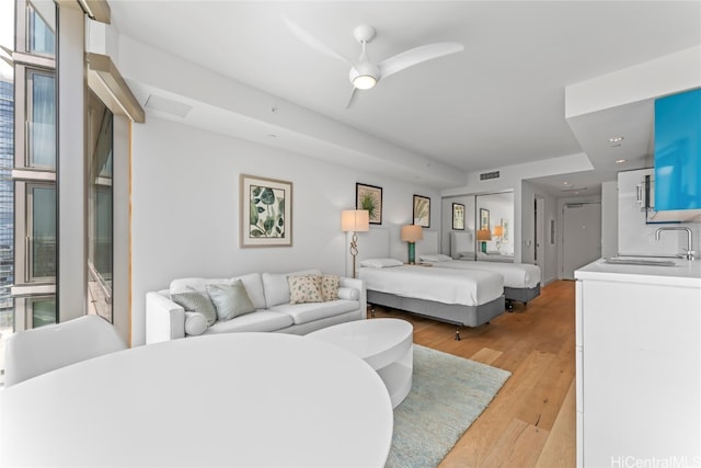 bedroom with ceiling fan, sink, and light hardwood / wood-style flooring