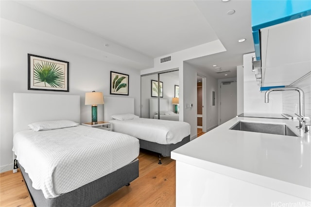 bedroom featuring light hardwood / wood-style flooring, a closet, and sink