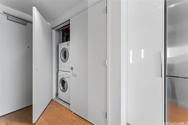 clothes washing area featuring stacked washer / drying machine and light wood-type flooring