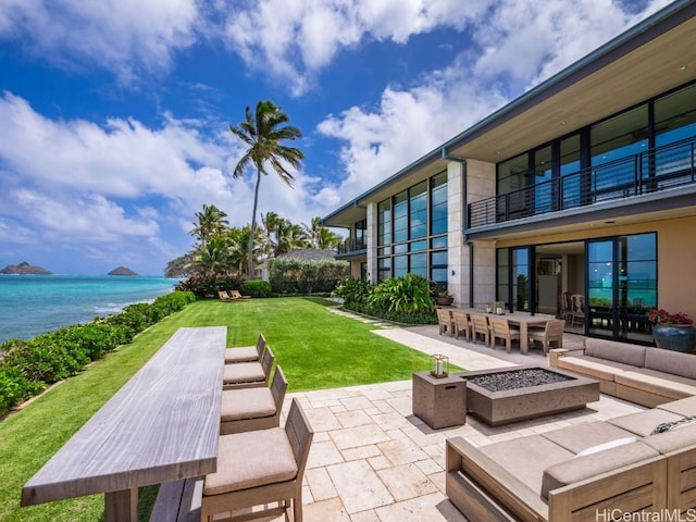 view of patio / terrace with an outdoor living space with a fire pit, a balcony, and a water view