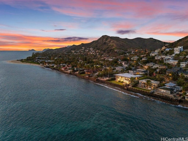 aerial view at dusk featuring a water and mountain view