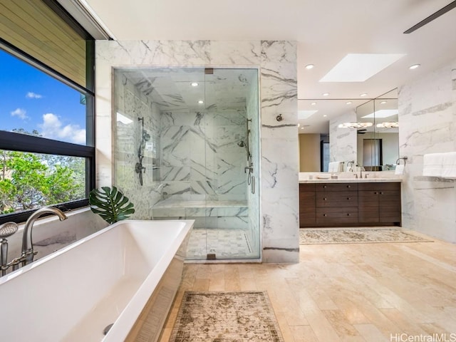 bathroom with vanity, shower with separate bathtub, and a skylight