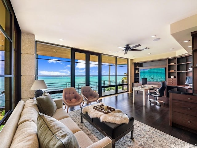 living room with wood-type flooring, built in features, expansive windows, and ceiling fan