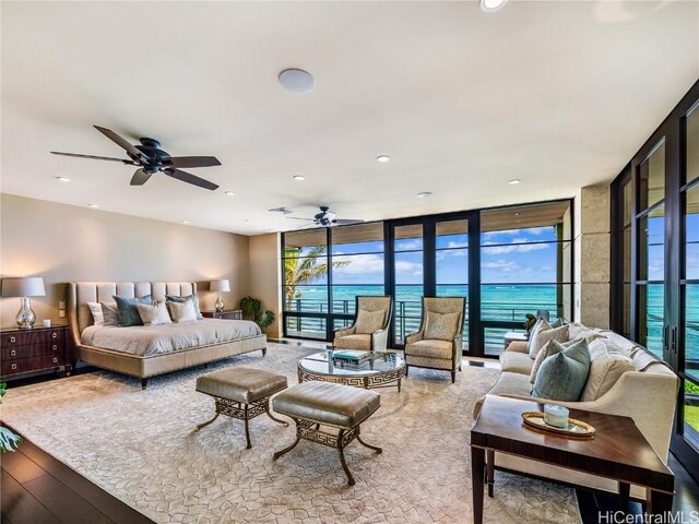 bedroom featuring a water view, light wood-type flooring, access to outside, and a wall of windows