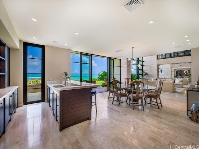 kitchen with a breakfast bar, pendant lighting, sink, floor to ceiling windows, and a center island with sink