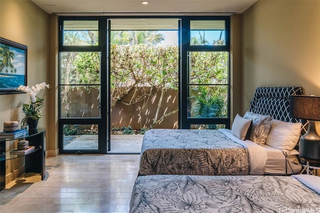 bedroom with wood-type flooring and a wall of windows