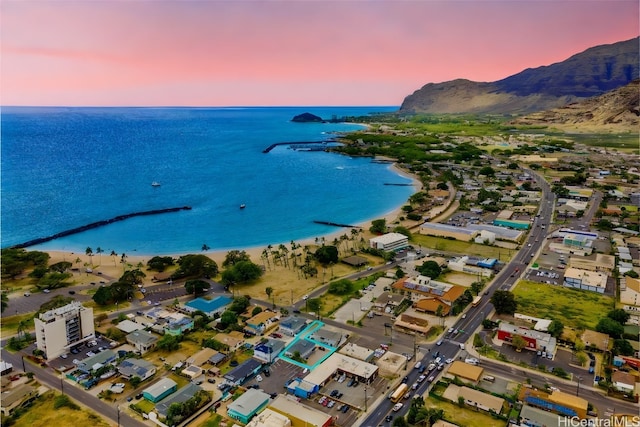 aerial view at dusk featuring a beach view and a water and mountain view