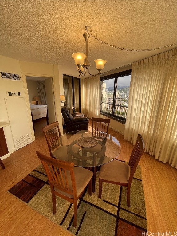 dining room featuring hardwood / wood-style floors, a chandelier, and a textured ceiling