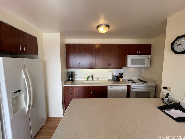 kitchen featuring sink, kitchen peninsula, hardwood / wood-style flooring, and white appliances