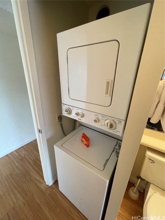 washroom with light hardwood / wood-style flooring and stacked washer and dryer