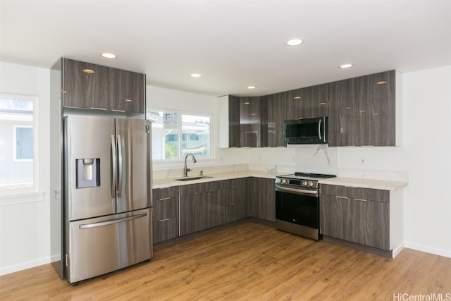 kitchen with sink, dark brown cabinets, stainless steel appliances, and light wood-type flooring