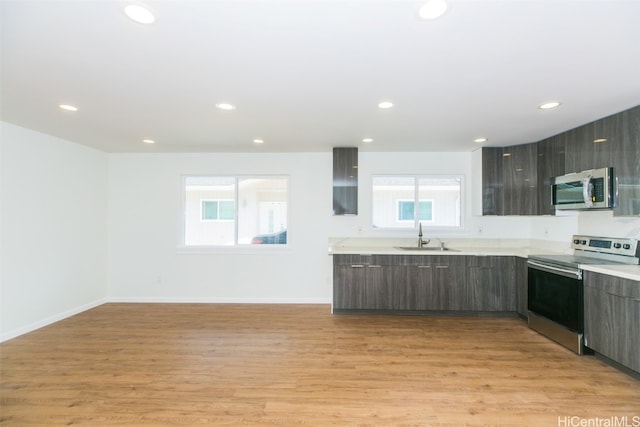 kitchen with appliances with stainless steel finishes, light hardwood / wood-style flooring, sink, and dark brown cabinets