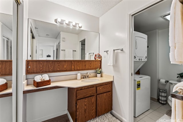 bathroom with vanity, tile patterned floors, a textured ceiling, and stacked washer and clothes dryer