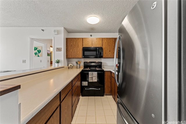 kitchen featuring a textured ceiling, black appliances, and light tile patterned floors