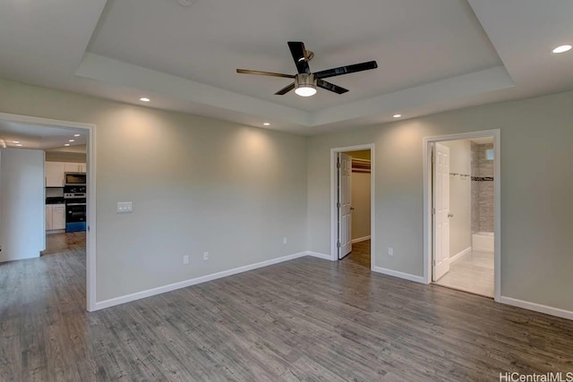 unfurnished room featuring ceiling fan, hardwood / wood-style flooring, and a raised ceiling