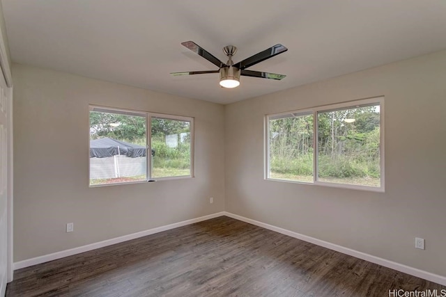 empty room with dark wood-type flooring, ceiling fan, and a healthy amount of sunlight