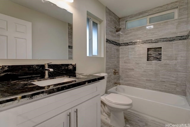 full bathroom with vanity, tiled shower / bath combo, and toilet