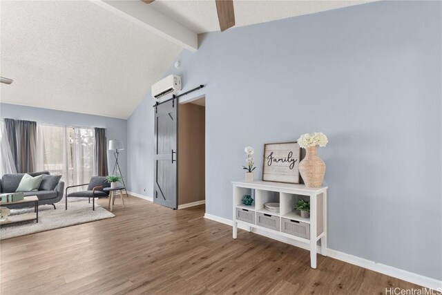 foyer entrance with a barn door, lofted ceiling with beams, an AC wall unit, hardwood / wood-style floors, and a textured ceiling