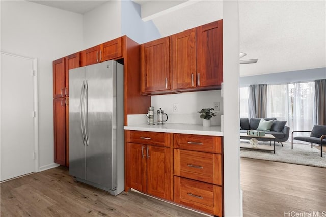 kitchen featuring lofted ceiling, light wood finished floors, light countertops, and freestanding refrigerator