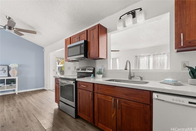 kitchen featuring sink, vaulted ceiling, ceiling fan, light wood-type flooring, and appliances with stainless steel finishes