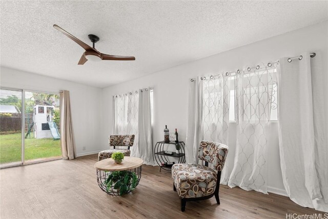 sitting room featuring ceiling fan, wood-type flooring, and a textured ceiling