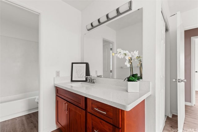 bathroom featuring a bathtub, wood finished floors, and vanity